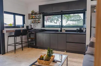 a kitchen with black cabinets and a table with a basket of fruit at Le Suite in Santa Teresa Beach