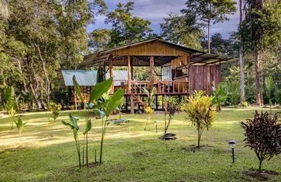 a house in the middle of a field with trees at Playa Ganadito Ecolodge in Drake