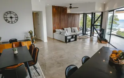 a living room with tables and chairs and a couch at Casa Nina Santa Teresa in Santa Teresa Beach