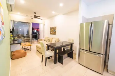 a kitchen and living room with a table and a refrigerator at SUNSET OCEAN VIEW CONDO in Jacó