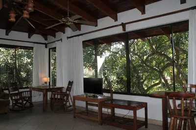 a screened in porch with tables and chairs and windows at Costa Verde Inn in San José