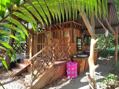 a wooden building with stairs and a palm tree at Jungle Tent 3x3, Latino Glamping & Tours, Paquera in Paquera