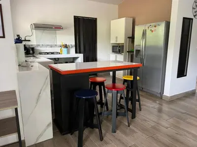 a kitchen with a counter with stools and a refrigerator at Encantadora Casa Amapolas in Cóbano