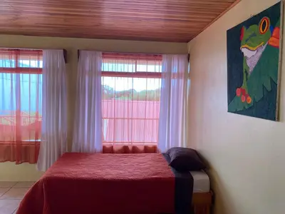 a bedroom with a bed with a red blanket and a window at Hotel La Puesta Del Sol B&B in Monteverde Costa Rica