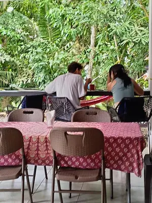 two people sitting at a table in a restaurant at Casajungla Hostel in Jacó