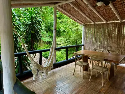a porch with a hammock and a table and chairs at Hotel El Manglar y Cantarana in Playa Grande