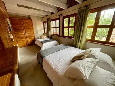 a bedroom with two beds in a room with windows at Hotel El Manglar y Cantarana in Playa Grande