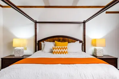 an orange and white bed in a bedroom with two lamps at La Esquina (3 minutes from Beach, perfect for a family getaway) in Tamarindo