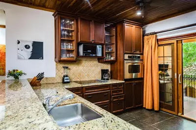 a kitchen with wooden cabinets and a counter top at La Esquina (3 minutes from Beach, perfect for a family getaway) in Tamarindo