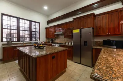 a kitchen with wooden cabinets and a stainless steel refrigerator at Hotel Majestad in San José