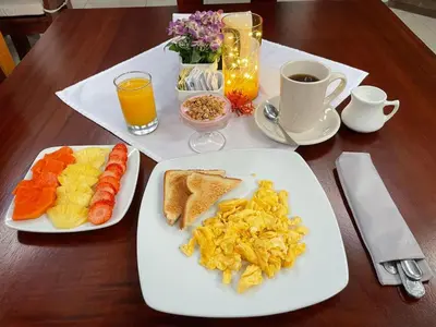 a table with two plates of breakfast foods and a cup of coffee at Hotel Majestad in San José