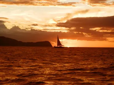 a sail boat in the ocean at sunset at Villa del Sueño in Playa Hermosa