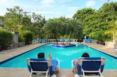 people sitting in chairs in front of a swimming pool at Villa del Sueño in Playa Hermosa