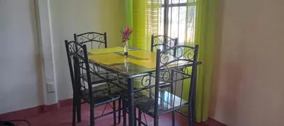 a dining room table with chairs and a yellow wall at Casita El Sonido de las Aves in Uvita