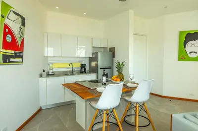 a kitchen with white cabinets and white bar stools at Adeluna Luxury Villas in Montezuma
