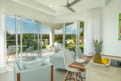 a living room with white furniture and glass windows at Adeluna Luxury Villas in Montezuma