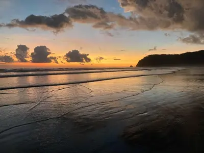 a sunset on a beach with the ocean at Palmetto Lodge in Playa San Miguel