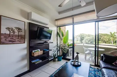 a living room with a couch and a tv at CR MARIPOSA RENTALS Cozy Retreat with Pool,Tennis,Gym,Free WiFi in Santa Ana