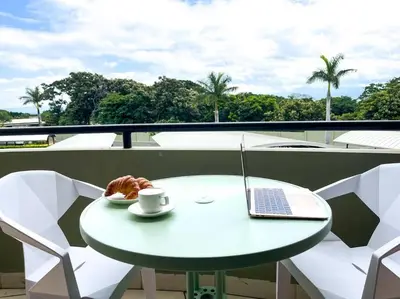 a table with a laptop and a cup of coffee on a balcony at CR MARIPOSA RENTALS Cozy Retreat with Pool,Tennis,Gym,Free WiFi in Santa Ana