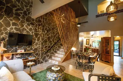 a living room with a stone wall at Villa Palmeras with jungle views pool near MA in Quepos