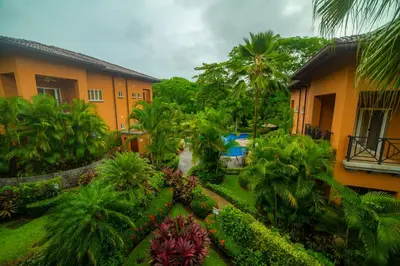 a garden in front of a building with palm trees at Veranda 3B 2 bdr Garden View in Los Suenos in Herradura