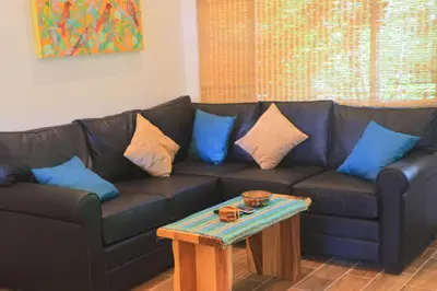a black couch with blue pillows and a table at Cabo Velas Estates in Playa Grande