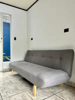a gray couch in a room with a window at Hotel Arenal Rabfer in Fortuna