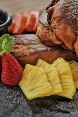 a plate of food with meat and fruit on a table at Hotel Arenal Rabfer in Fortuna