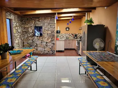 a kitchen with wooden tables and a stone wall at Casa Flores in Heredia