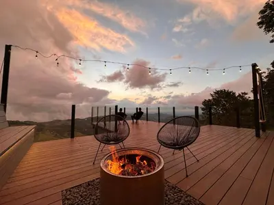 a fire pit on a deck with a sunset in the background at Amalú Luxury View Cabins in Monteverde Costa Rica
