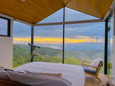 a bedroom with a large window with a camera at Amalú Luxury View Cabins in Monteverde Costa Rica