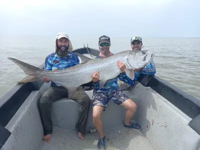 three men sitting in a boat holding a fish at Casa Chilamates 2.0 in Tortuguero
