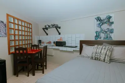 a bedroom with a bed and a table and a kitchen at Oasis Diverse Adult Retreat in Quepos