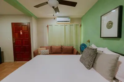 a bedroom with a white bed and a couch at Oasis Diverse Adult Retreat in Quepos