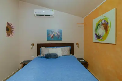a bedroom with a bed with a blue comforter at Oasis Diverse Adult Retreat in Quepos