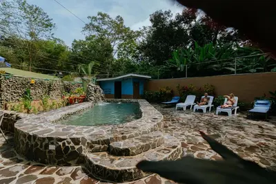 a pool in a yard with two people sitting in chairs at Oasis Diverse Adult Retreat in Quepos