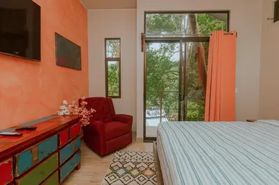 a bedroom with a bed and a red chair at Oasis Diverse Adult Retreat in Quepos