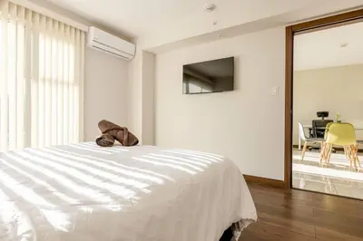 a white bedroom with a bed and a dining room at New & Modern APT - 100 MBPS 15 min from airport in San José