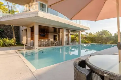 a swimming pool with chairs and an umbrella next to a building at New & Modern APT - 100 MBPS 15 min from airport in San José