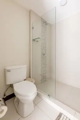 a white bathroom with a toilet and a shower at New & Modern APT - 100 MBPS 15 min from airport in San José
