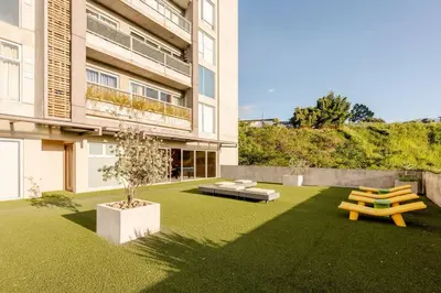 a yard with two benches and a building at New & Modern APT - 100 MBPS 15 min from airport in San José