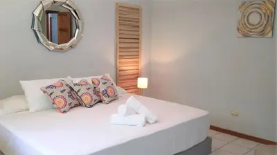a bedroom with a white bed with pillows and a mirror at Space One in Manuel Antonio