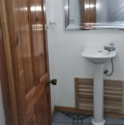 a bathroom with a sink and a wooden door at Space One in Manuel Antonio