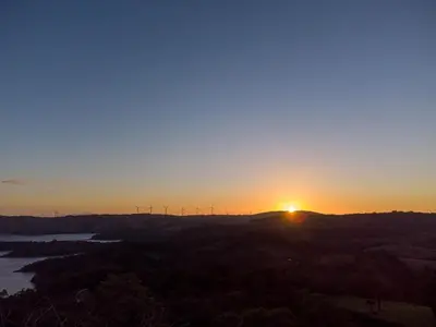a sunset on a hill with windmills in the background at Vista Lago Arenal in Piedras