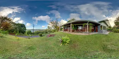 a house on top of a grassy field at Vista Lago Arenal in Piedras