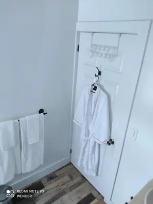 a white robe hanging on a door in a bathroom at Green House by W. in Heredia