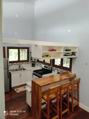 a kitchen with white cabinets and a wooden table at Green House by W. in Heredia