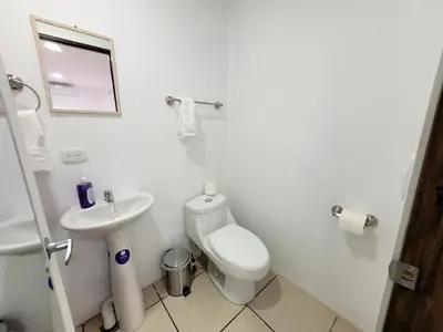 a white bathroom with a toilet and a sink at La Fonda Apartments in Fortuna