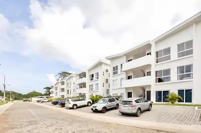 a row of cars parked in a parking lot in front of a building at Modern 2BR Condo - minutes from Jaco Beach - PRIME location in Jacó