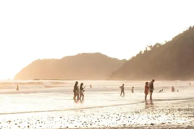 a group of people standing in the water at the beach at Modern 2BR Condo - minutes from Jaco Beach - PRIME location in Jacó
